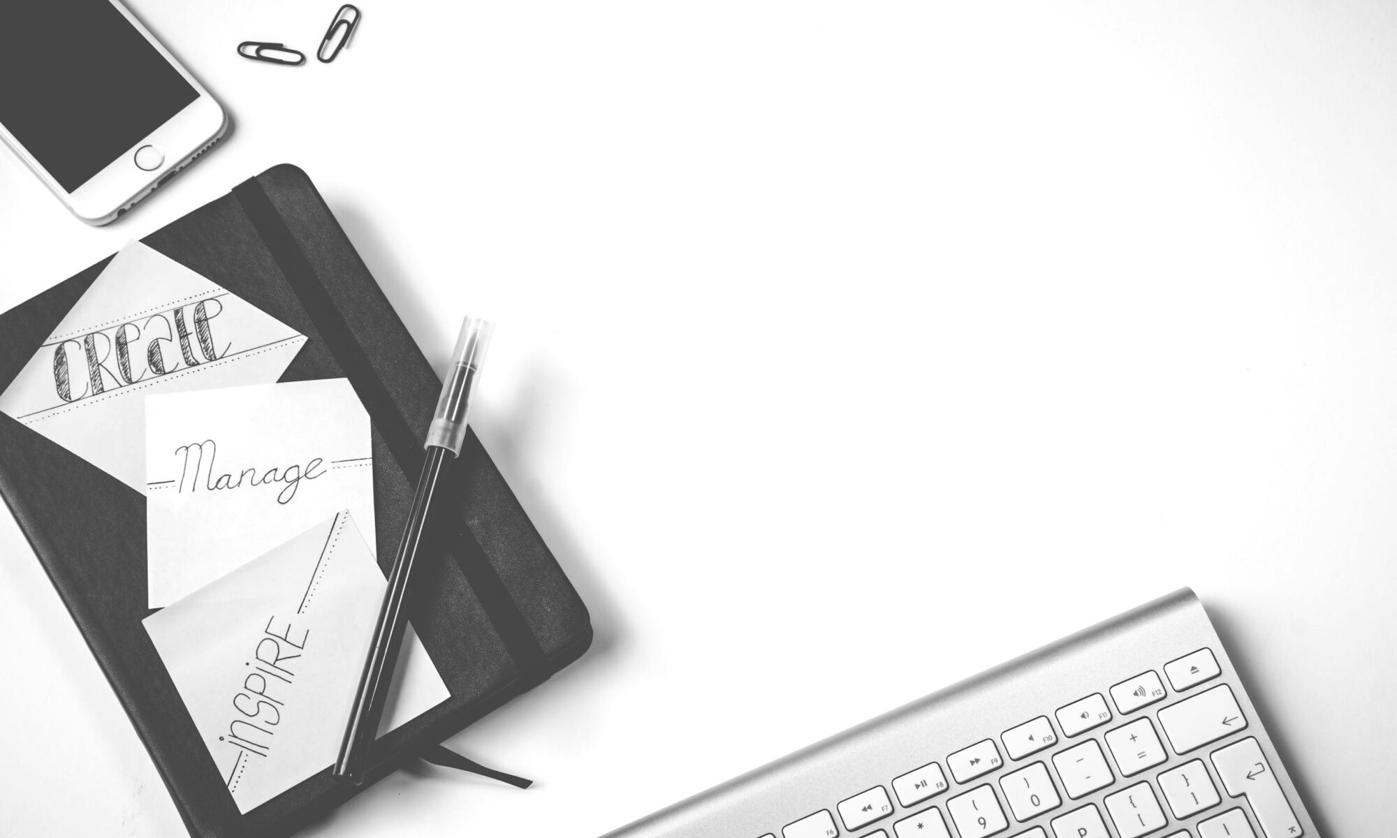 Minimalist flat lay of an office desk with notebook, keyboard, and smartphone.